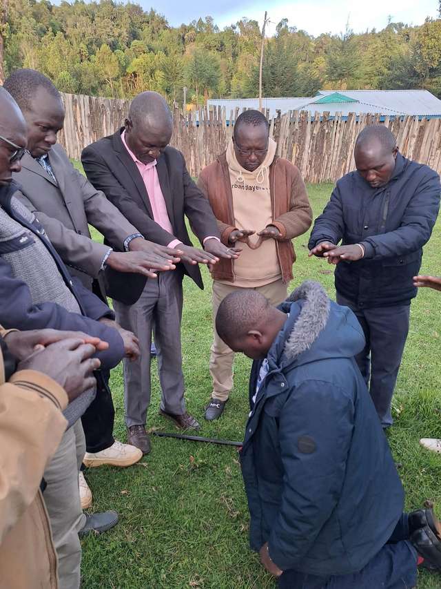 Long’ole kneels as elders stretch their hands over him in blessing
