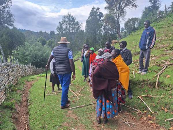 Long’ole, with a walking stick, talks to women wrapped in shawls on a village path